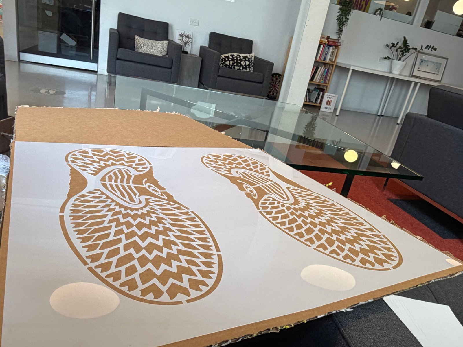 White stencil with paired shoe-sole cutouts resting on a worktable during preparation.