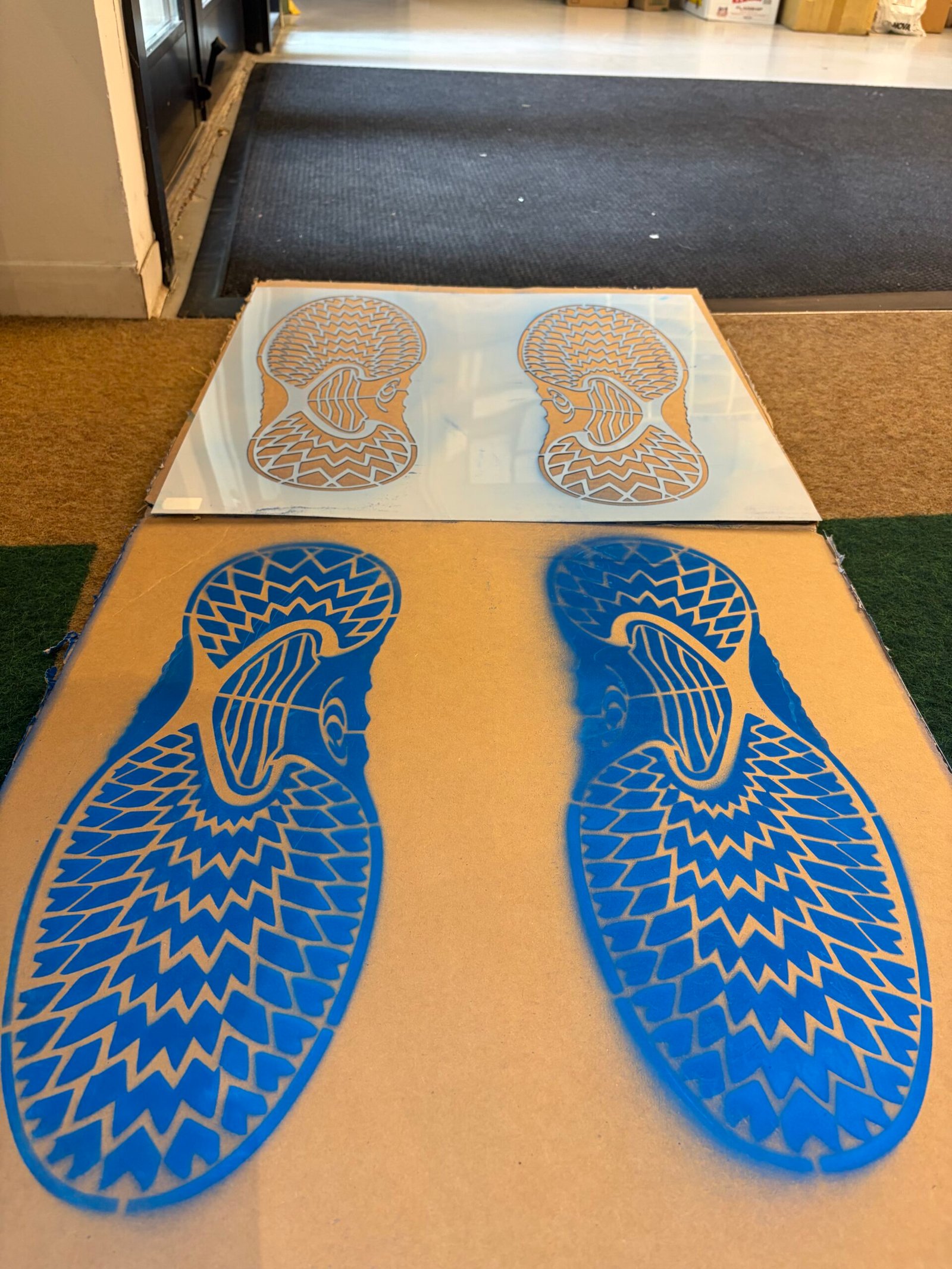 White footprint stencil displayed behind its blue sample print on a board.