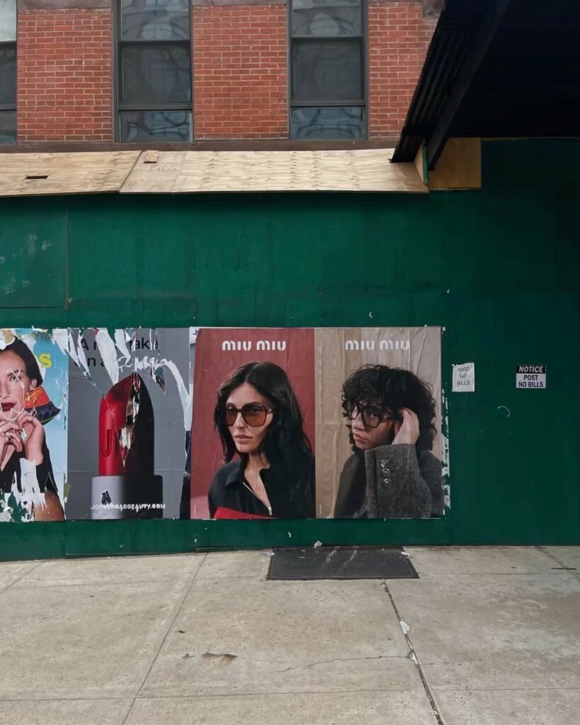 Miu Miu fashion posters displayed on a green street barricade
