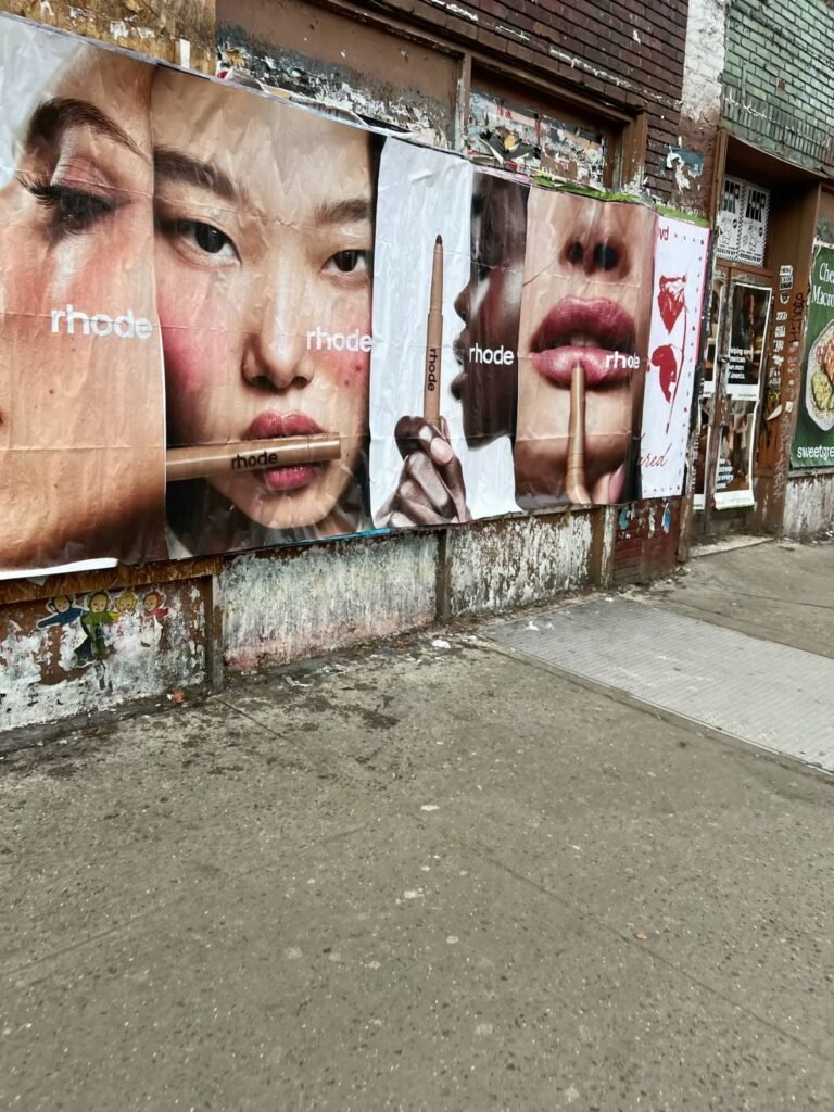 Rhode beauty posters displayed side by side on a street wall